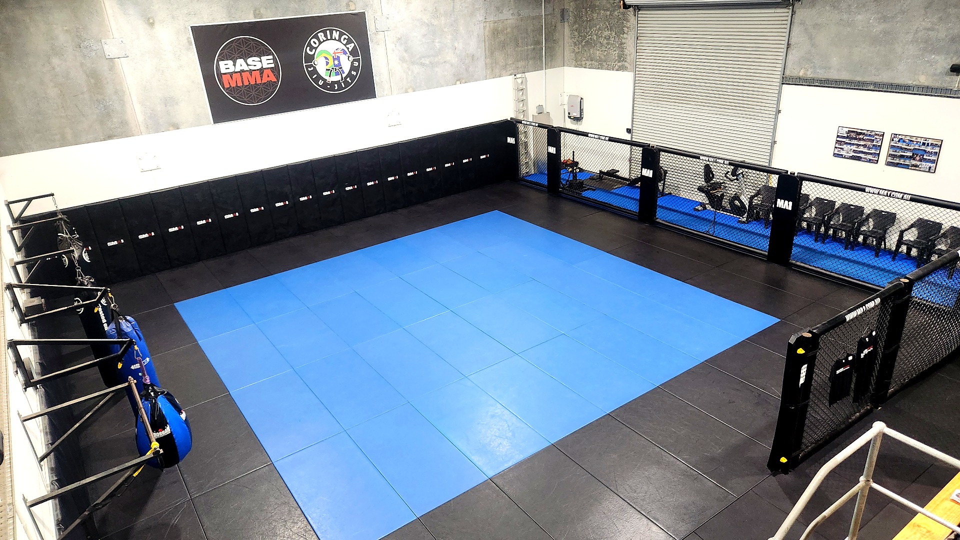 Wide view of the BASE MMA main training mats and cage area