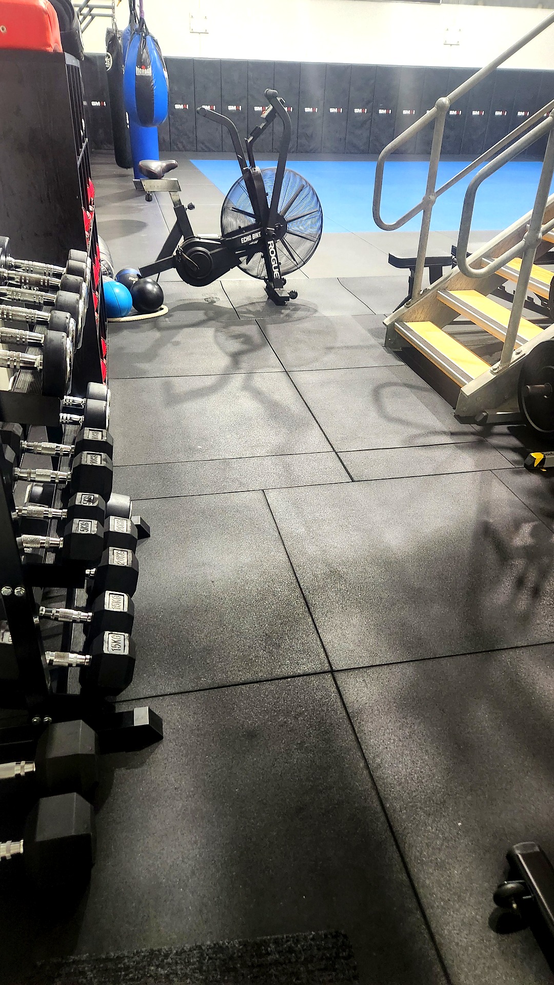 Strength and conditioning area with dumbbells and an echo bike at BASE MMA